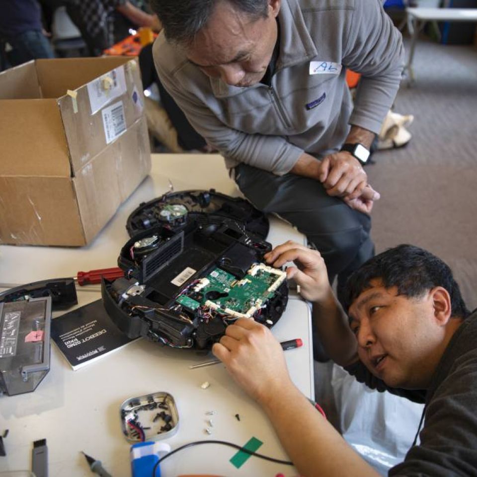 Fixit Clinic volunteer helps participant repair electronic device - photo by Kathryn Styer Martinez for KQED