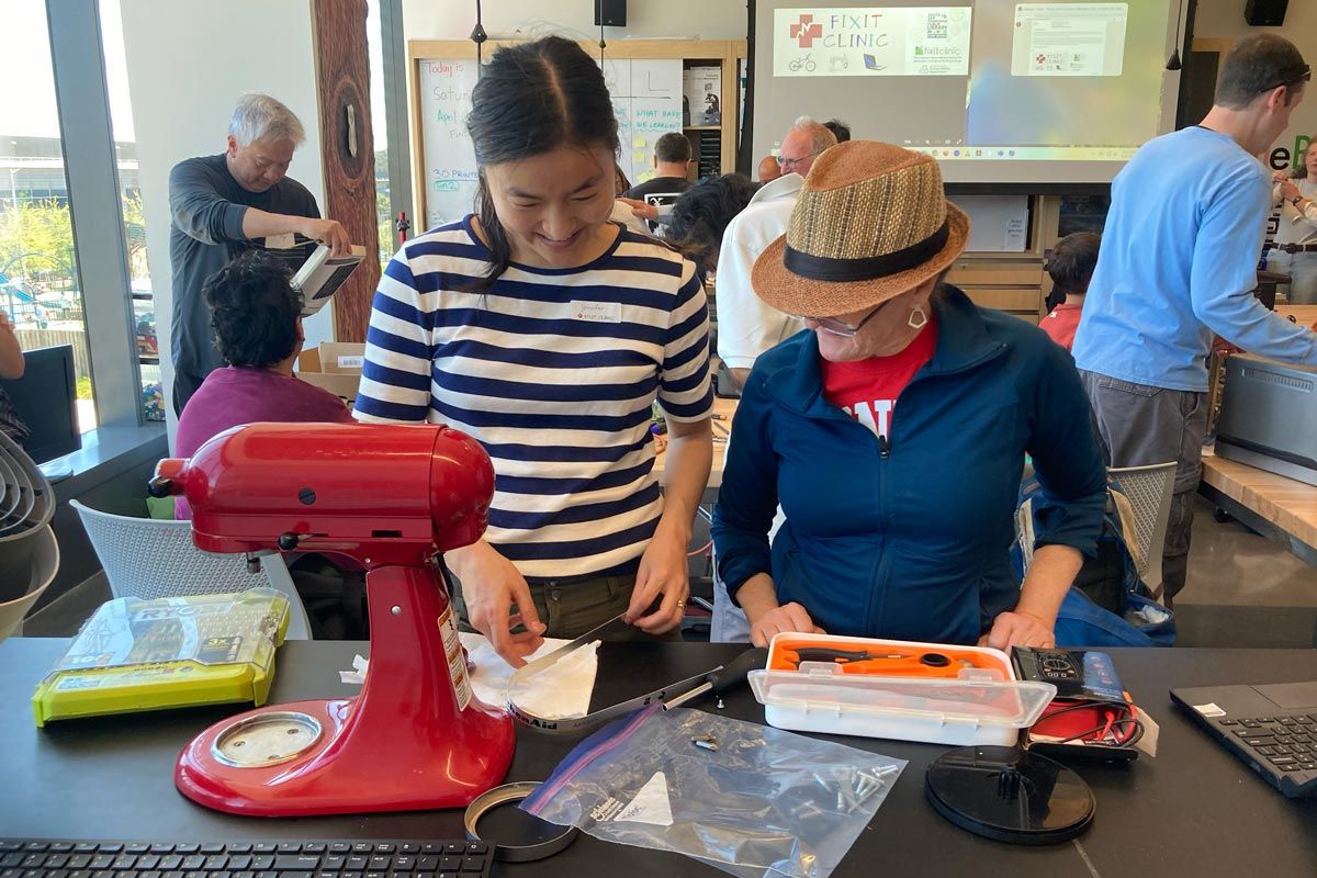 Two women work together to fix a standing mixer at San Mateo County Fixit Clinic