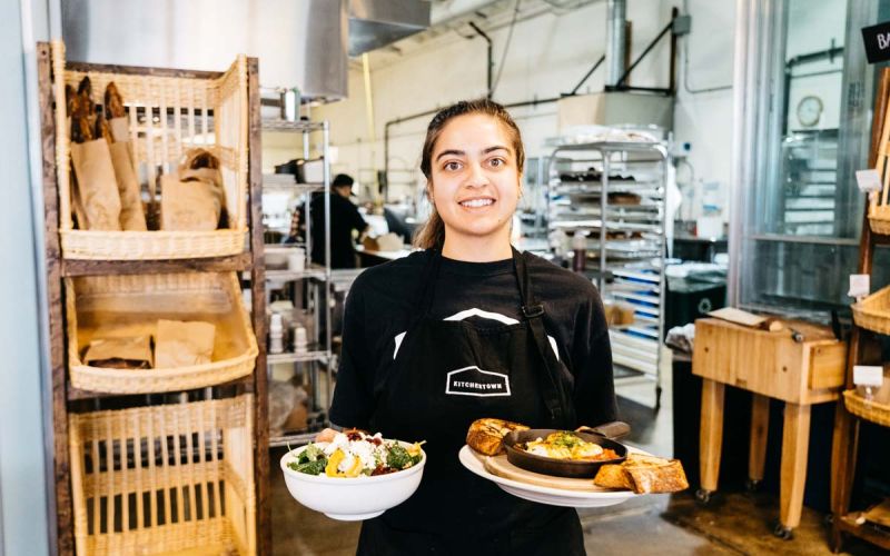 female food service worker holding up two dishes of food
