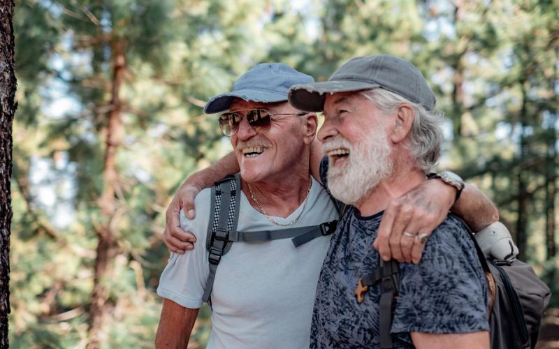 two senior men on forest hike strike a pose for a photo