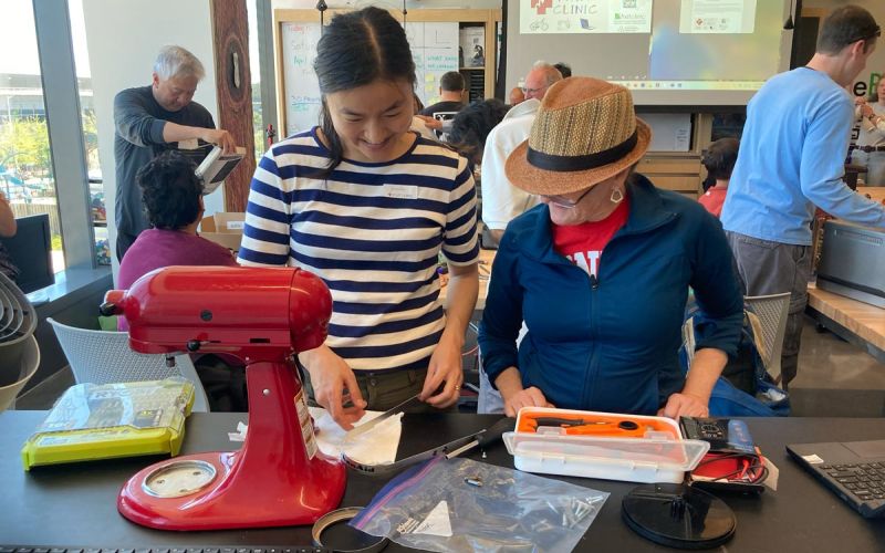 Two women work together to fix a standing mixer at San Mateo County Fixit Clinic