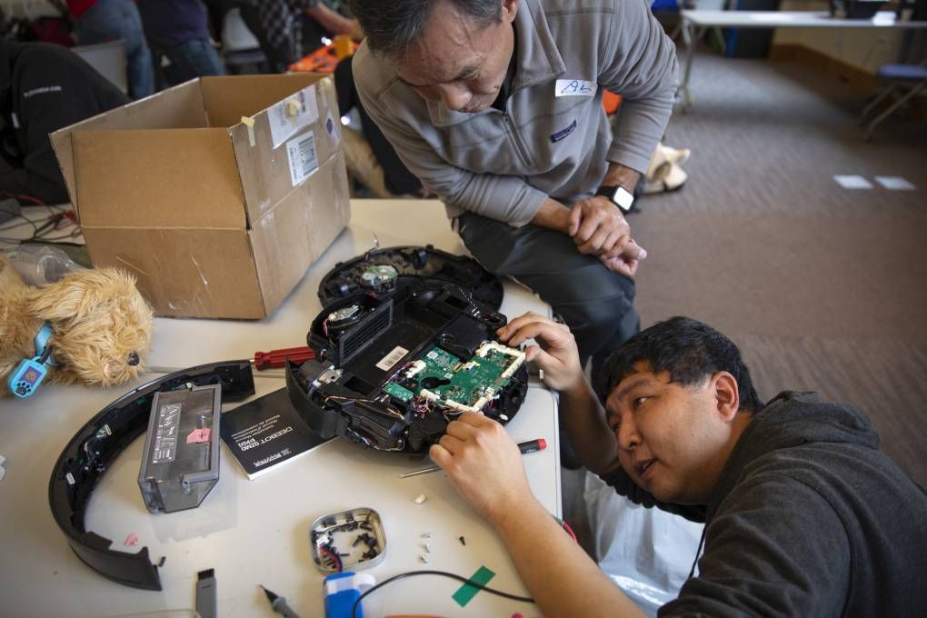 Fixit Clinic volunteer helps participant repair electronic device - photo by Kathryn Styer Martinez for KQED