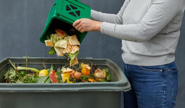 woman adding food waste to compost bin